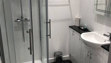 Ein modernes Badezimmer mit einer Duschkabine, einer weißen Toilette und einem Waschbecken mit schwarzer Arbeitsplatte.