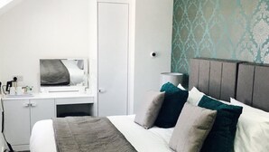 A modern hotel room with a large bed, a desk, and a mirror.