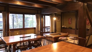 Et traditionelt japansk værelse med møbler i træ, tatami-måtter og store vinduer med udsigt over naturen.