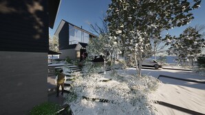 Et moderne hus med et stort glasvindue, en indkørsel og en bil i baggrunden.