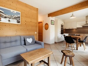 A modern living room with a sofa, a coffee table, and a dining area with chairs and a table.