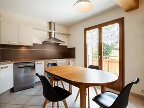 A modern kitchen with a dishwasher, a stove, and a dining table with chairs.