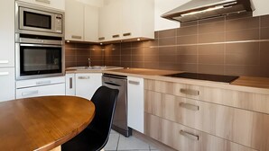 Eine moderne Küche mit eingebauten Geräten, einem Holztisch und einem schwarzen Stuhl.