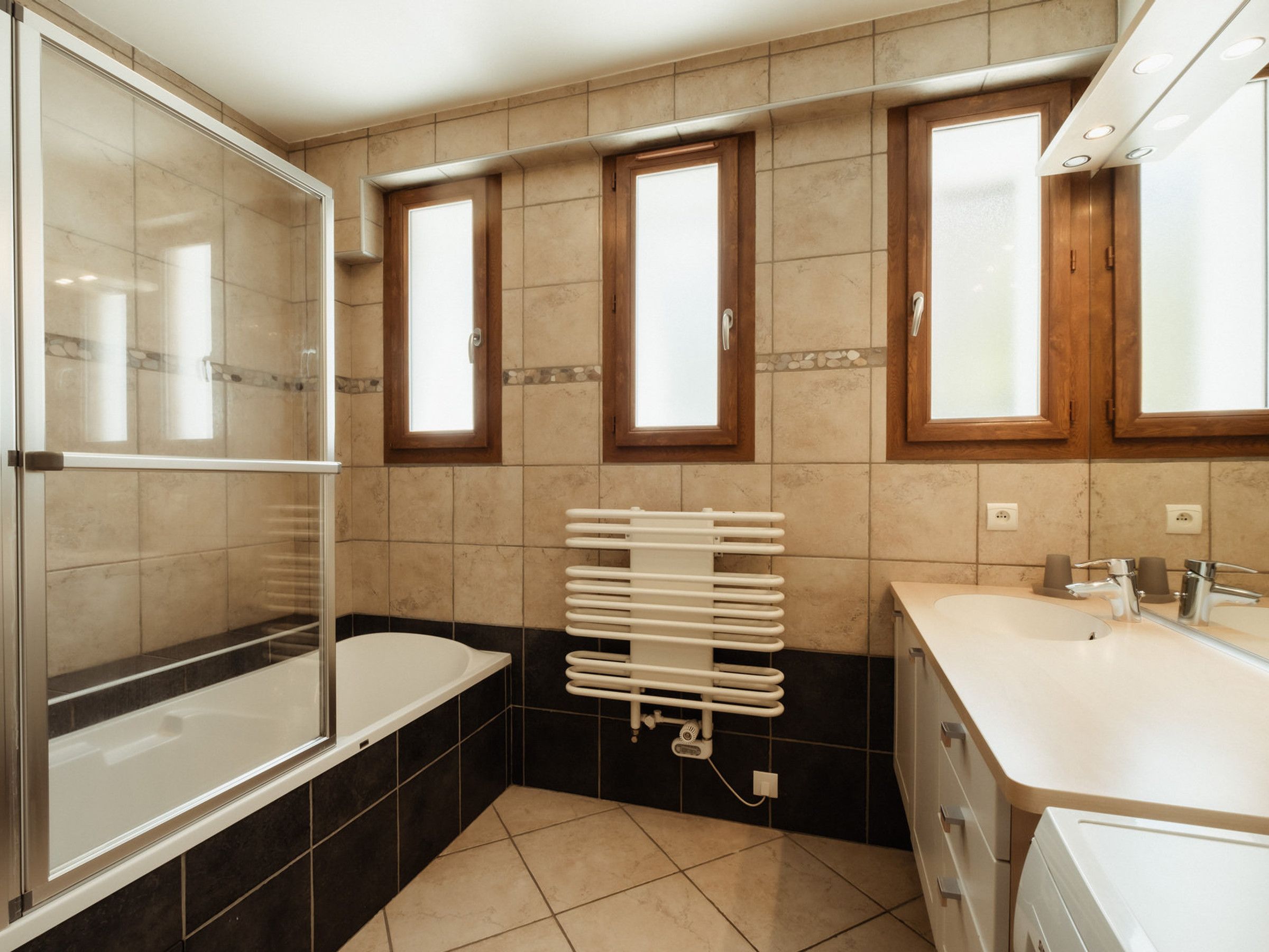 A modern bathroom with a bathtub, a shower, a sink, and a window.