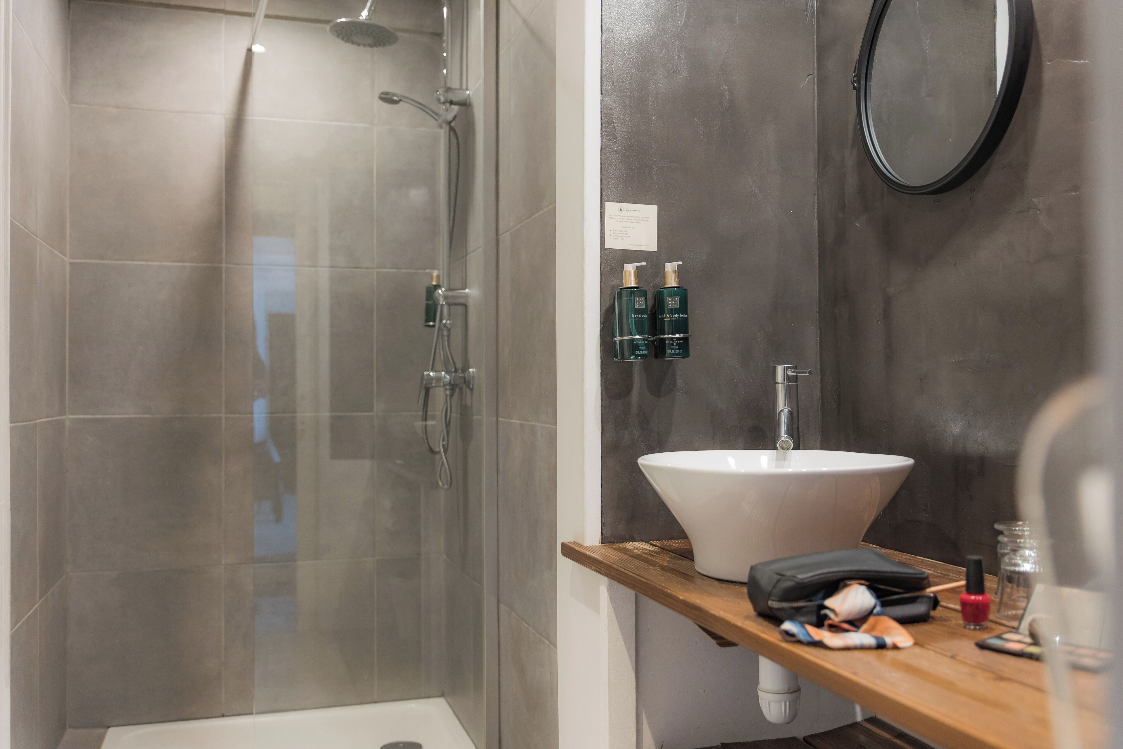 A modern bathroom with a glass-enclosed shower, a white sink, and a wooden vanity.