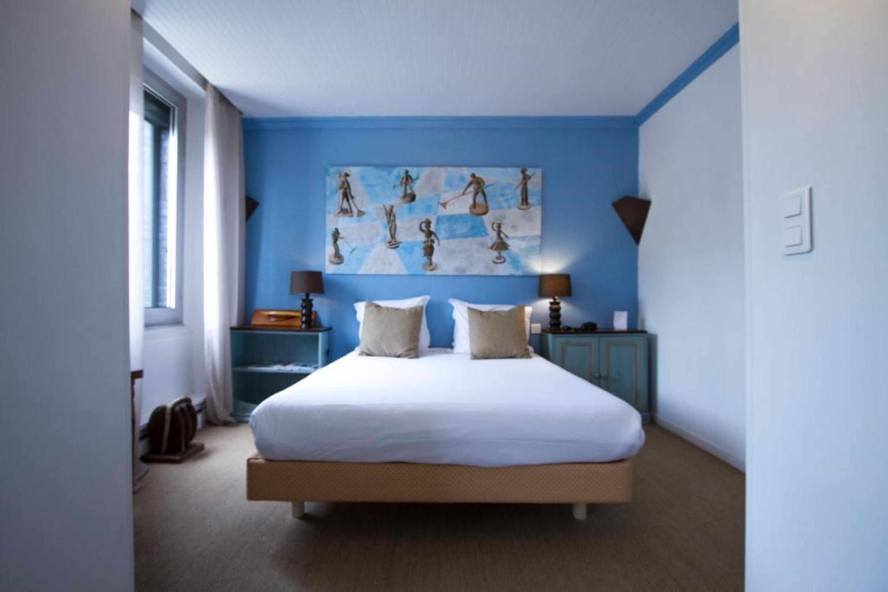 Een slaapkamer met een groot bed, twee nachtkastjes, een kunstwerk aan de muur en een raam met gordijnen.