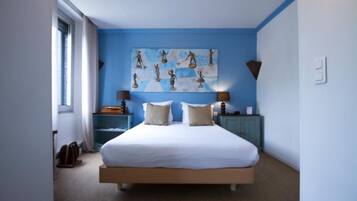 Een slaapkamer met een groot bed, twee nachtkastjes, een kunstwerk aan de muur en een raam met gordijnen.
