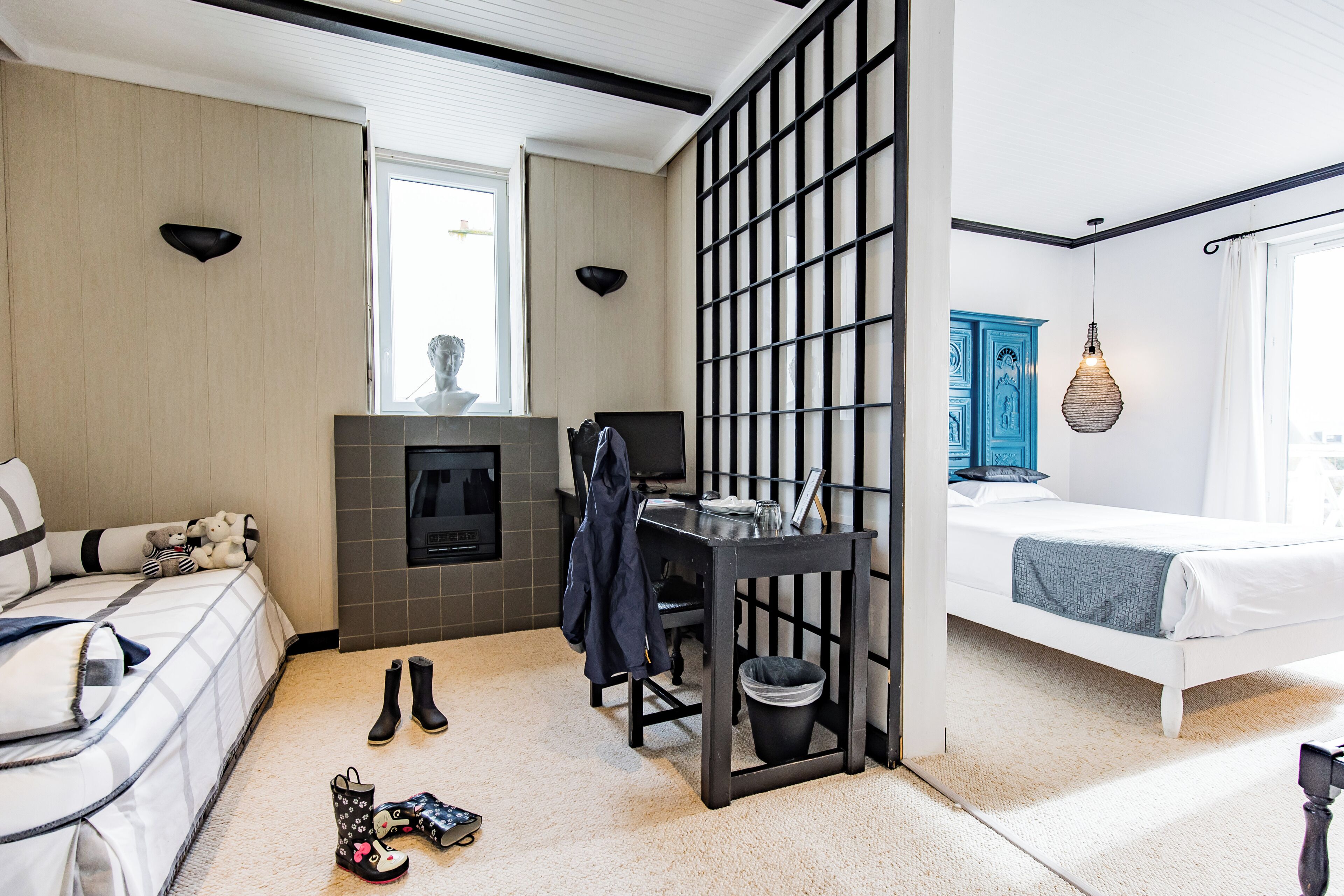 Una habitación de hotel moderna con cama, escritorio, silla, chimenea y un ventanal grande.
