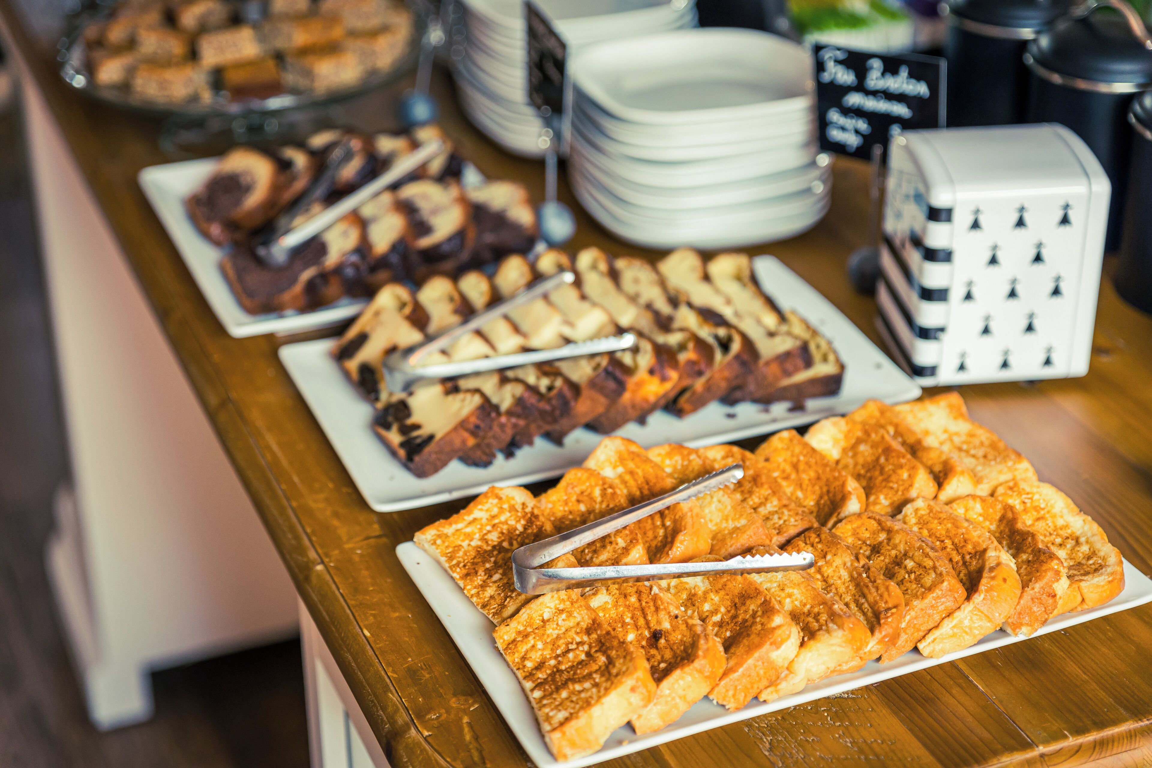 A buffet table with various food items, including bread and desserts, and a sign indicating the buffet is open.