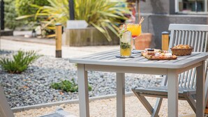 An outdoor patio with a table set for two, surrounded by chairs, and a bench. - Hotel de Charme Sud Bretagne Pornichet La Baule (Pornichet)