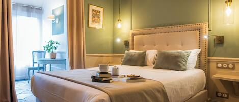 A neatly made bed with pillows, a bedside table with a lamp, and a framed picture on the wall.