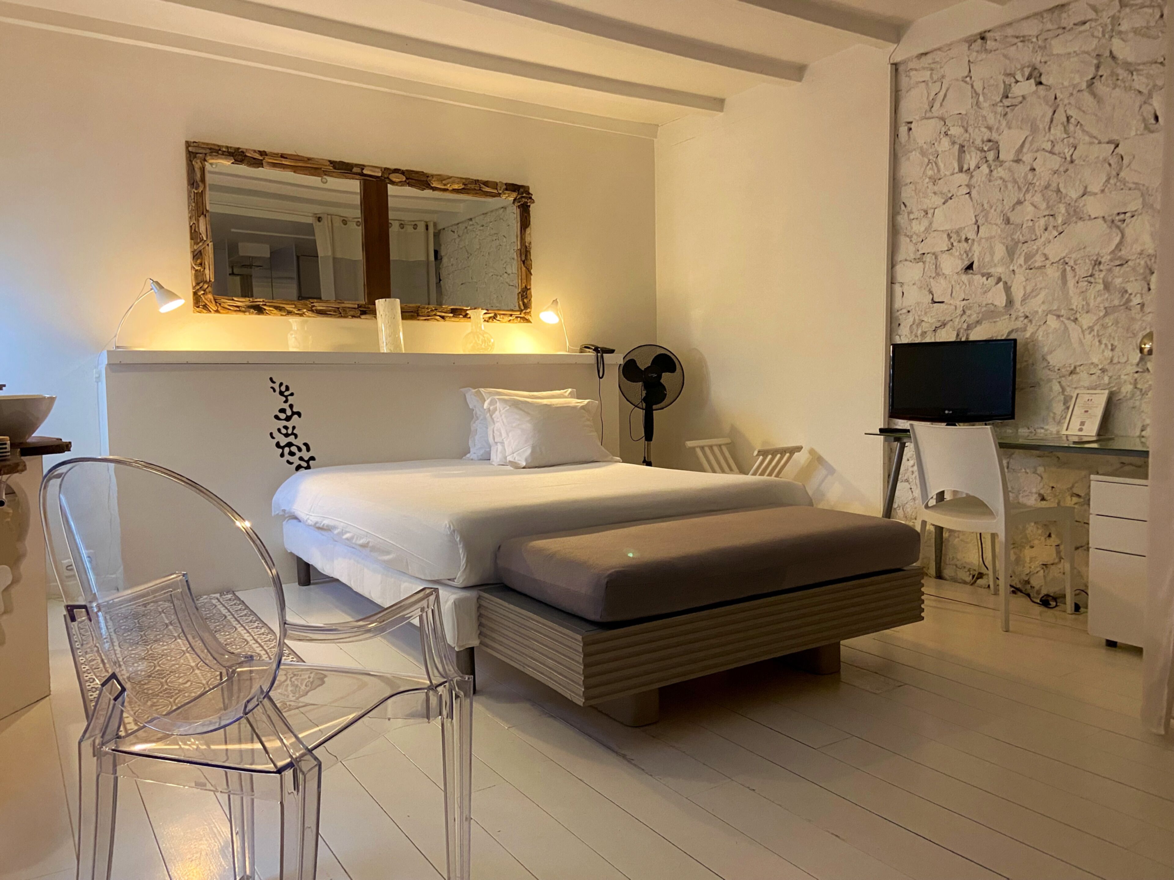 A modern bedroom with a bed, a desk, a chair, and a television.