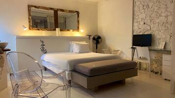 A modern bedroom with a bed, a desk, a chair, and a television.