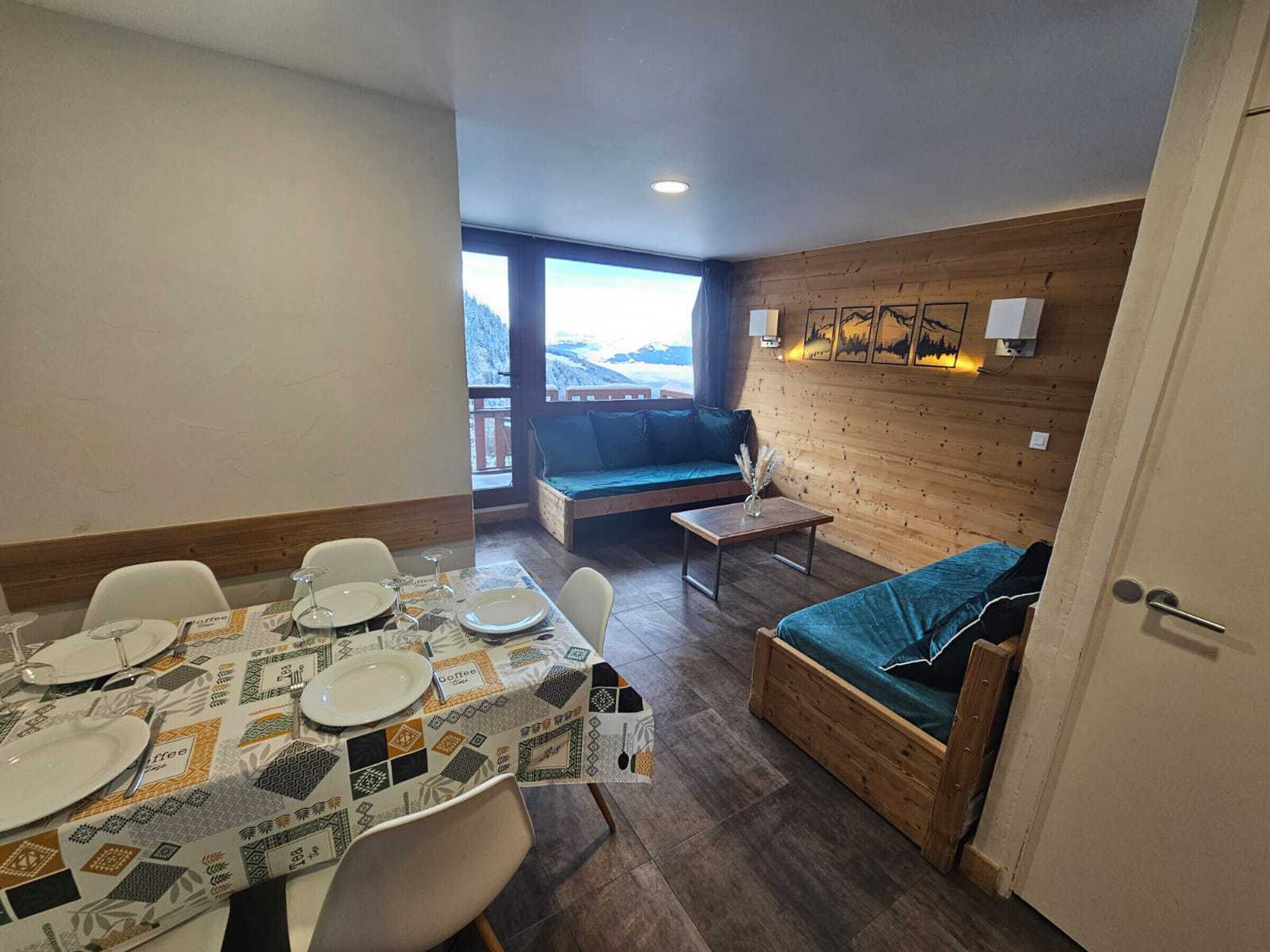 Une pièce chaleureuse avec une table à manger dressée pour quatre personnes, un canapé et une petite table sur laquelle est posé un vase.