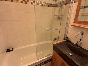 Un bagno con doccia vetrata, una vasca da bagno, un lavabo e uno specchio.
