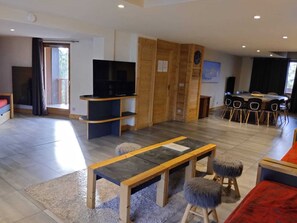 Un salon moderne doté d’un téléviseur à écran plat, d’un coin repas avec une table et des chaises, et d’une cloison en bois.