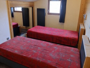 Une chambre avec deux lits, une fenêtre, une porte et une petite table.