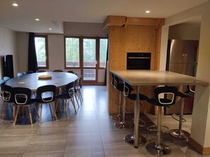 A modern kitchen with a central island, bar stools, and a dining area with a round table and chairs.