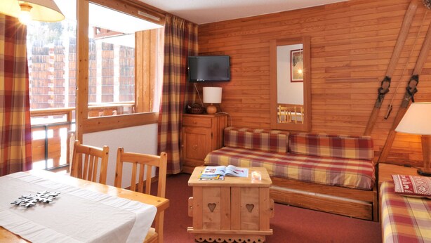 A cozy room with a wooden interior, a sofa, a table, and a television. - 2-room apt for 5 in station center with balcony and pool (Plagne Bellecôte)