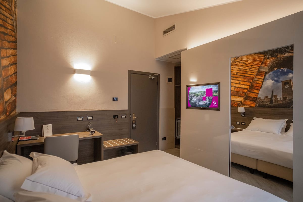 Une chambre d’hôtel avec un lit, un bureau, une chaise, une télévision et un miroir.