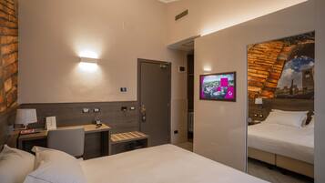Una habitación de hotel con cama, escritorio, silla, televisión y espejo.