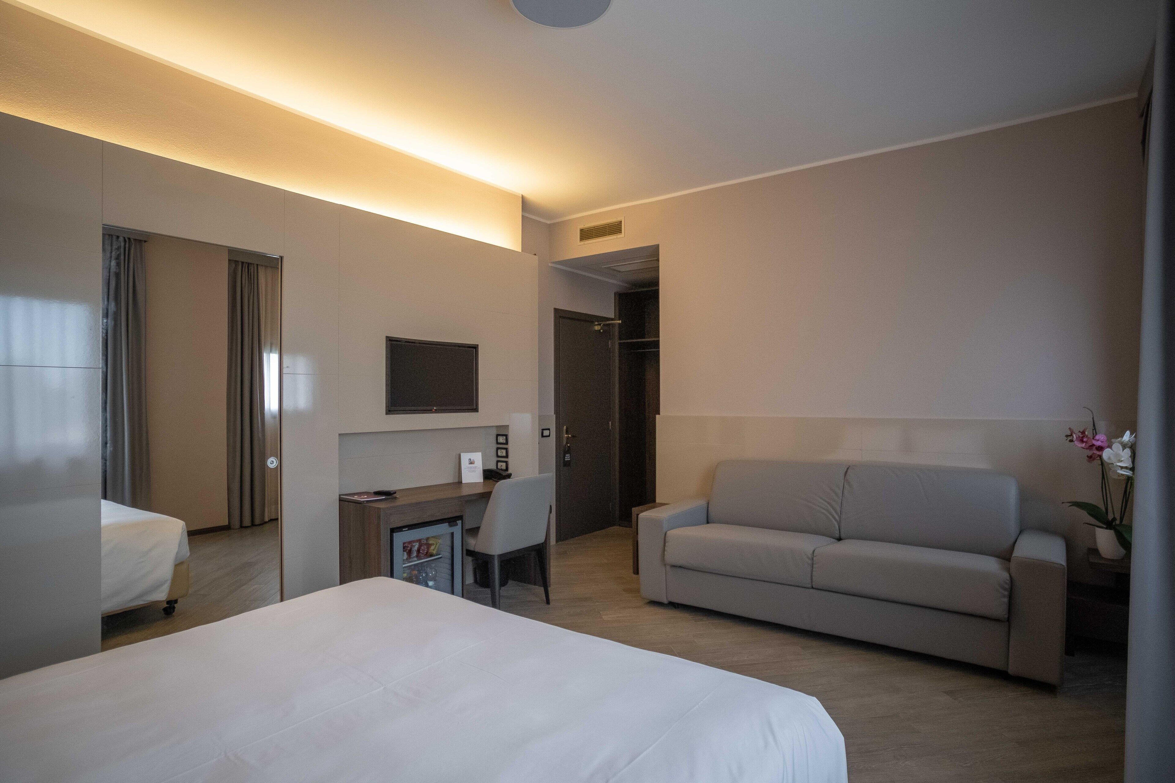 Una habitación de hotel con cama, escritorio, sofá y zona de ducha.
