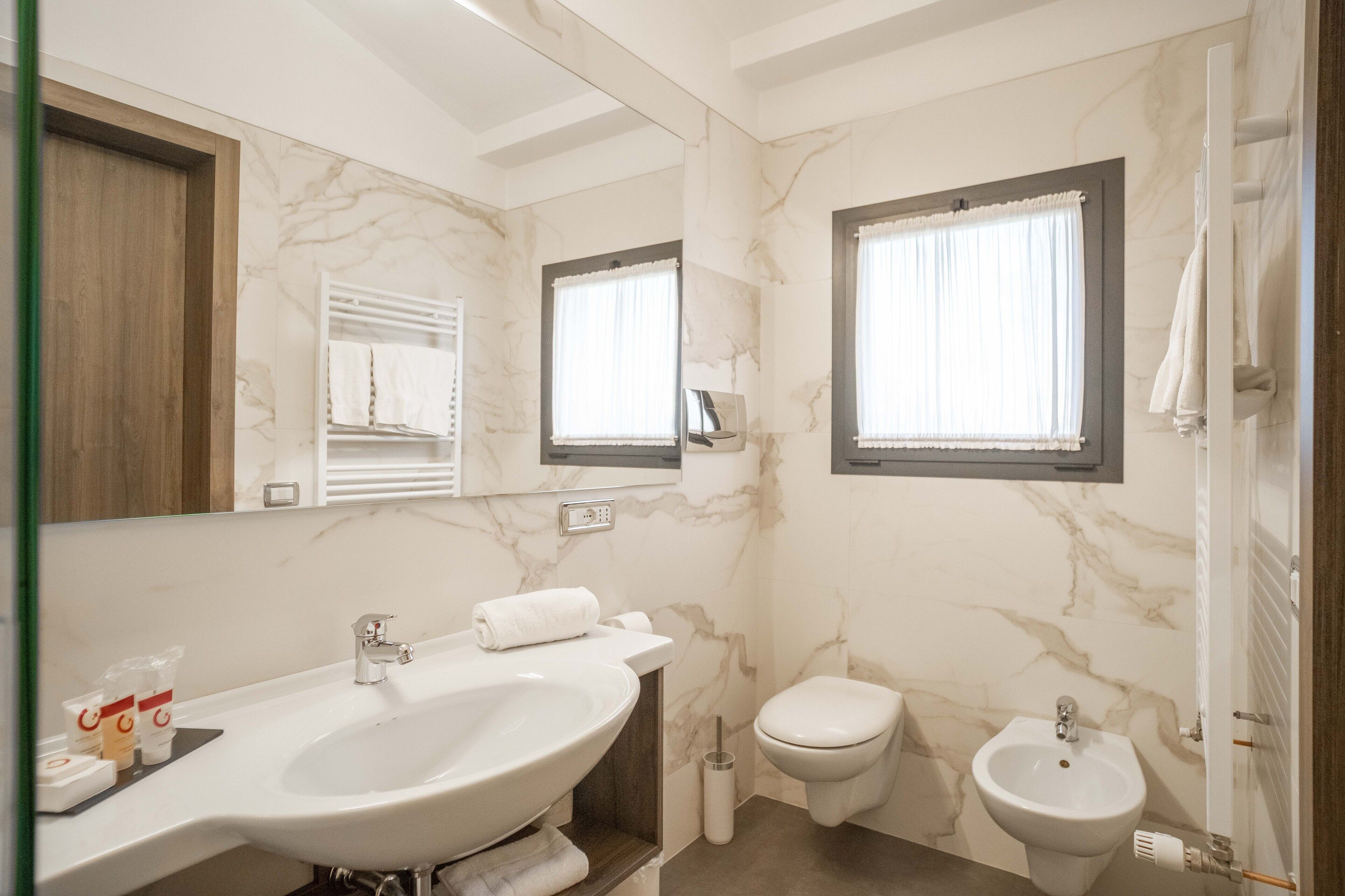 A bathroom with a large sink, toilet, bidet, and a mirror.