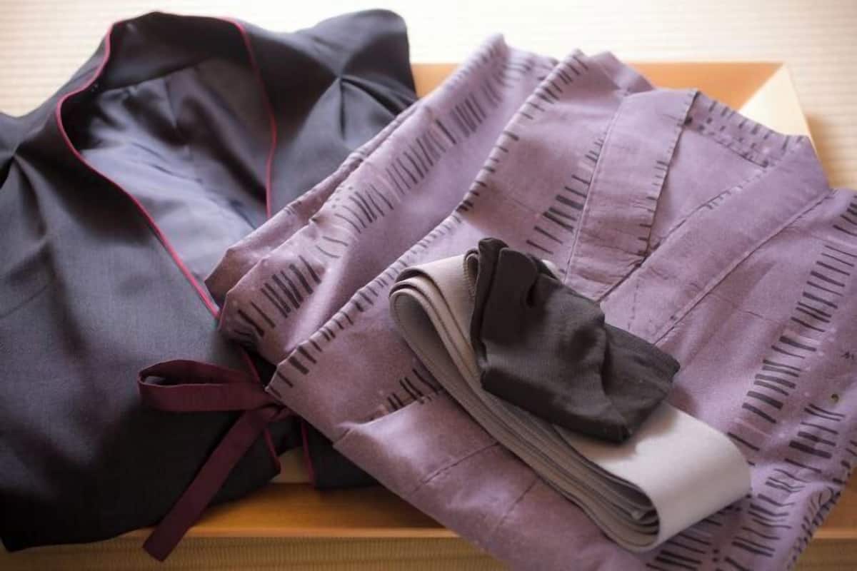 Una prenda morada doblada con cuidado, con cuello oscuro y un lazo color burdeos sobre una superficie de madera.