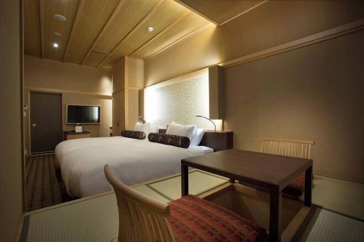 Una habitación de hotel con una cama grande, un escritorio, una silla, un televisor y una ventana.