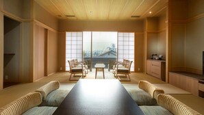 Perinteinen japanilaistyylinen huone, jossa on tatamimatto lattiana, matala pöytä sekä kaksi tatamimattoa tyynyineen.