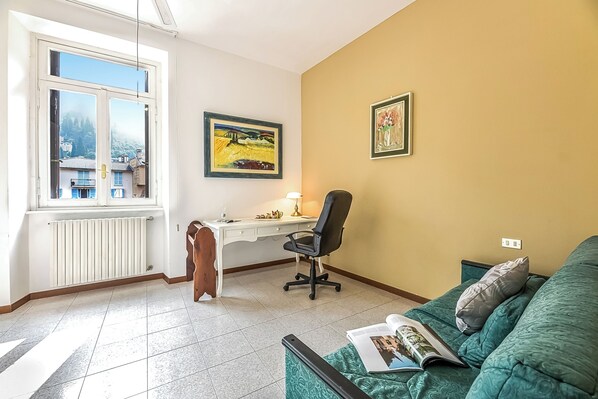 Una habitación con escritorio, silla y sofá verde con una revista.