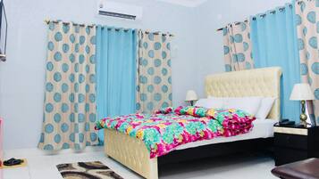 A bedroom with a bed, curtains, a bedside table, and a lamp.