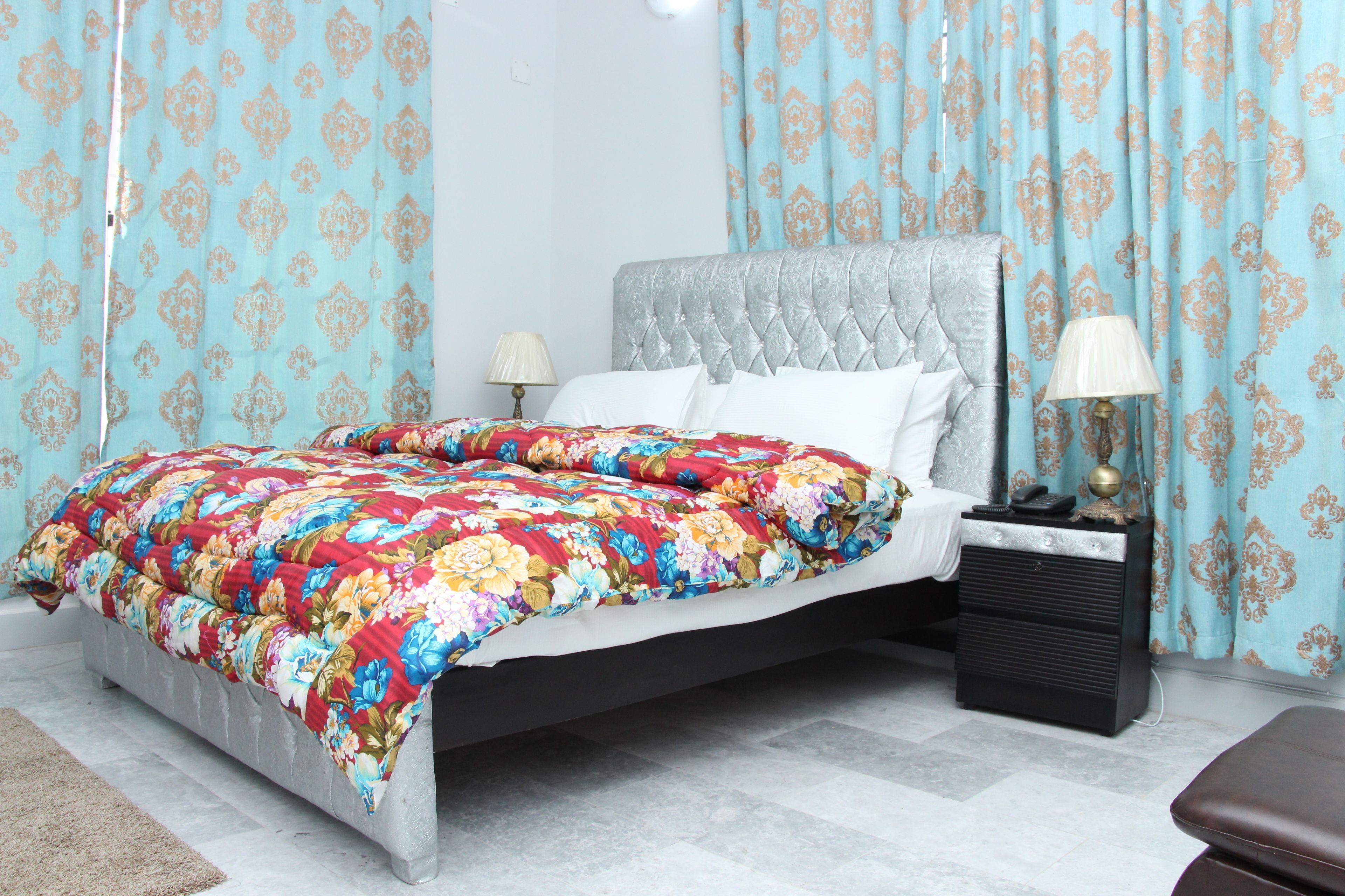 A bed with a floral comforter, a tufted headboard, and two bedside lamps.