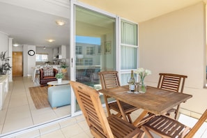 A modern apartment with a wooden dining table, chairs, and a sliding glass door leading to a balcony.