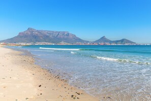 A beach with clear blue waters and a mountain in the background.