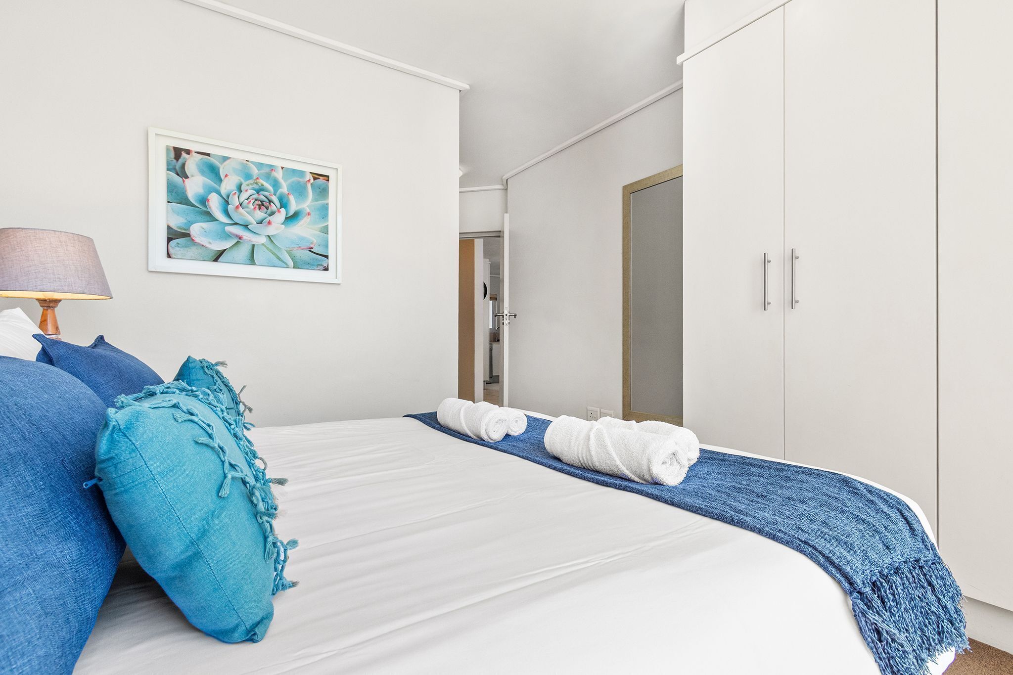 Uma cama bem arrumada com roupa de cama azul e branca, um cobertor azul e um travesseiro azul.