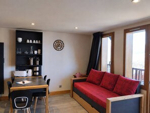 Ein gemütlicher Wohnbereich mit Esstisch, Stühlen, einer Couch und einem Bücherregal.