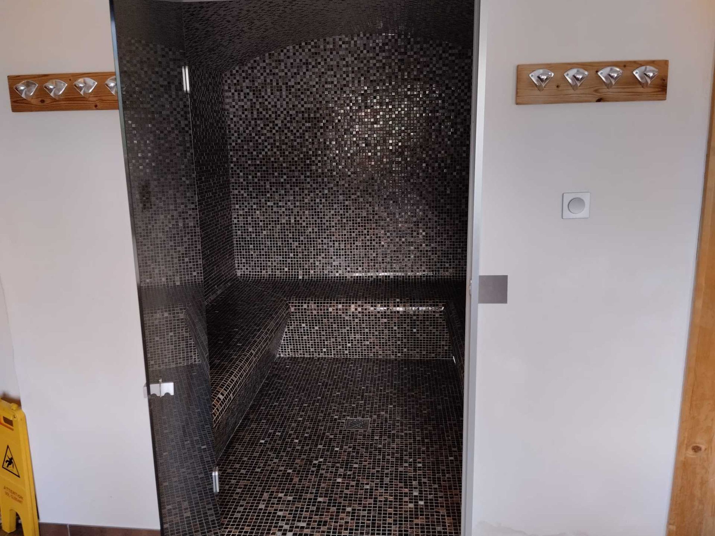A room with a tiled floor, a wooden door, and a wall-mounted light switch.
