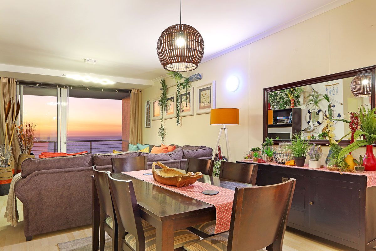 Ein modernes Wohnzimmer mit Essbereich, großen Fenstern und Blick sowie verschiedenen Pflanzen.