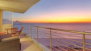 A balcony with a view of the ocean and a distant mountain at sunset. - Horizon Bay 1201 (Cape Town)