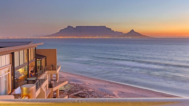 A beachfront hotel with a view of a mountain and city lights in the distance. - Horizon Bay 1201 (Cape Town)
