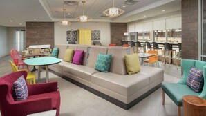 A modern lounge area with a sofa, chairs, and tables. - Home2 Suites by Hilton Edison (Edison)