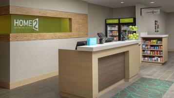 Zona de recepción de hotel con mostrador, minibar y estación de bebidas de autoservicio.