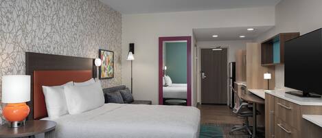 A hotel room with two beds, a desk, a television, and a bathroom visible through an open door.