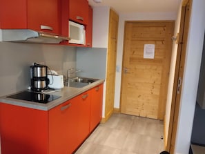 A compact kitchen with a microwave, coffee maker, and sink.