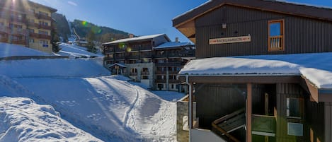 A snow-covered building labeled "Backgammon" with a wooden exterior and a balcony.