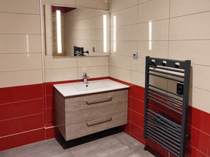 A bathroom with a white sink, wooden vanity, red-tiled walls, and a black towel rack. - Renovated studio near slopes with wellness, pets allowed (La Plagne Montchavin Les Coches)