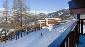 Ein schneebedecktes Skipistenfeld mit einer Berghütte im Hintergrund.