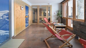 Ein Korridor mit Holzwänden, einer Bergmalerei und einem roten Lounge-Sessel.