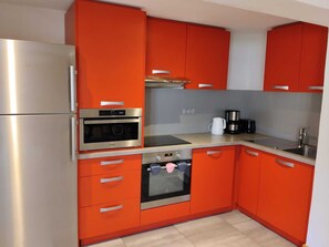 A kitchen with red cabinets, a stainless steel refrigerator, an oven, and a coffee maker. - Renovated apartment near slopes with wellness area and parking (La Plagne Montchavin Les Coches)